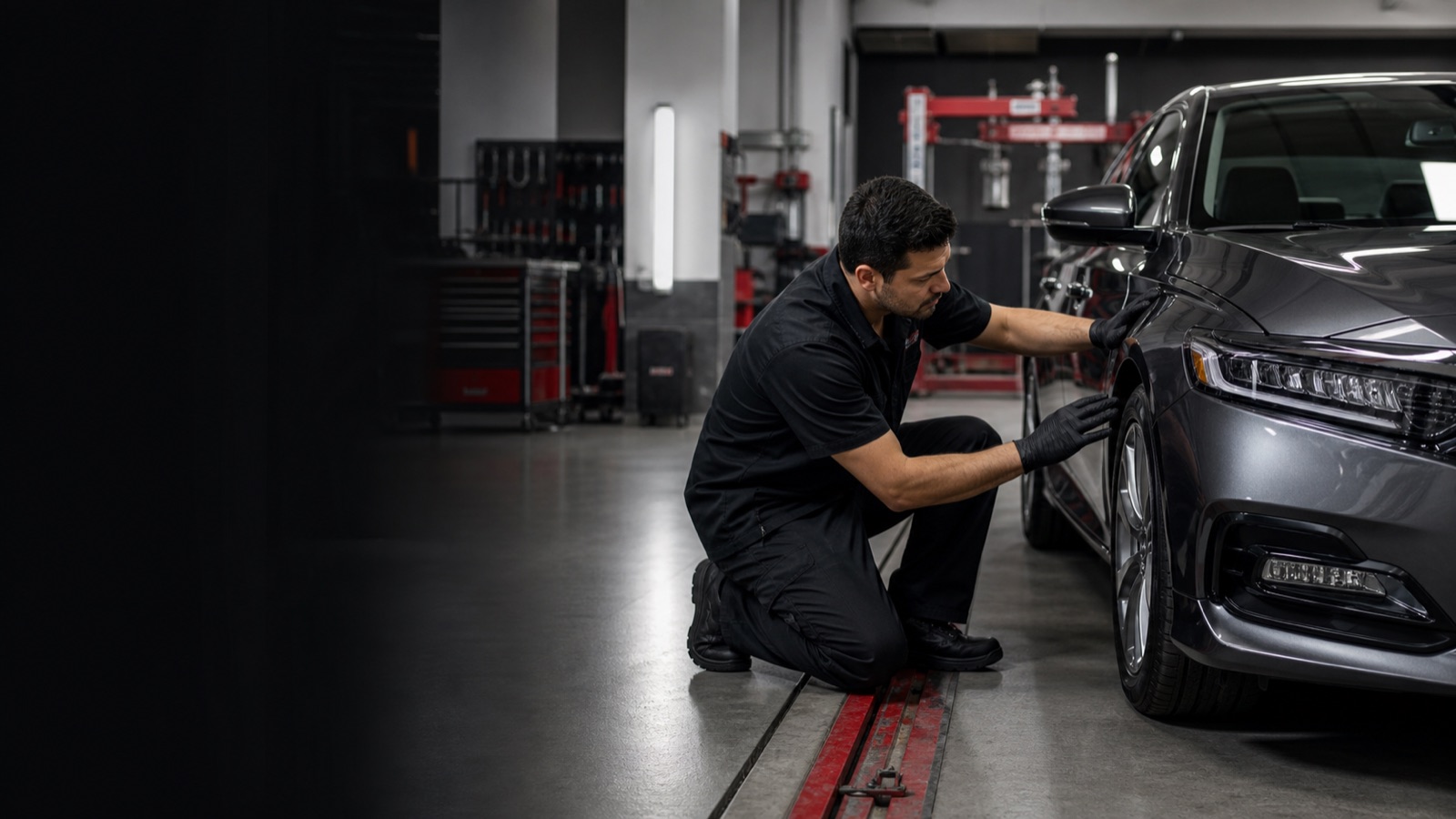 Auto collision technician inspecting a repaired vehicle in a modern body shop